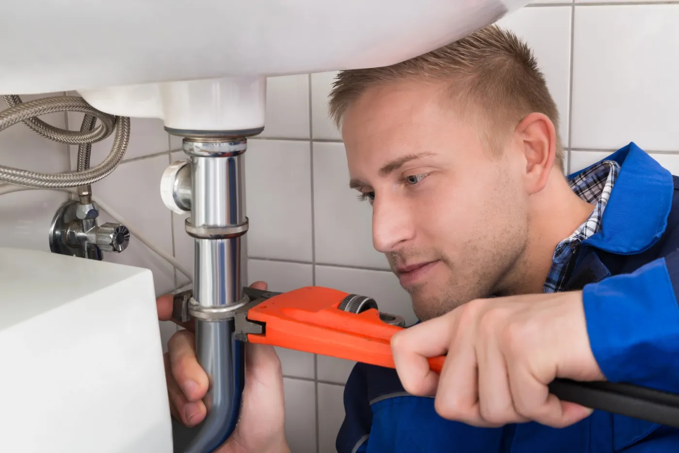 Plombier intervenant sur la plomberie sous un lavabo à Vincennes (94300)